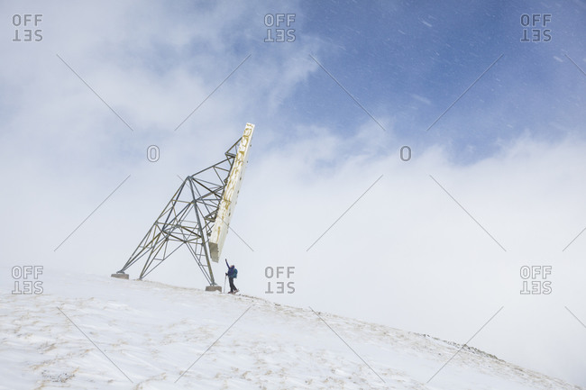 Woman reaches for a radio repeater on the summit of McMillan Peak, San Juan National Forest, Colorado