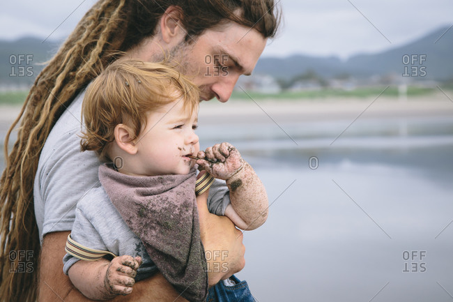 Man holding his toddler as he eats sand