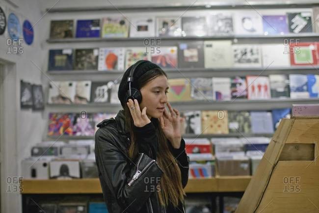 Young woman listening to headphones in record store
