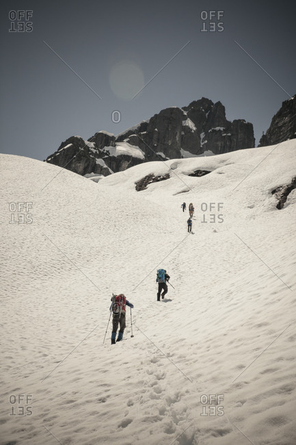 Six climbers cross a snow patch en route to climb Trio Peak in British Columbia, Canada