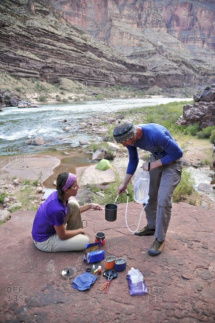 Hikers cook dinner on a cliff-pinched patio above camp and the Colorado River near Deer Creek Falls in the Grand Canyon