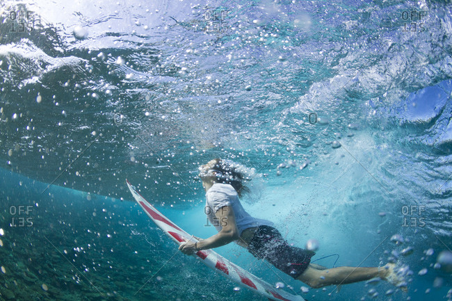 Close up, underwater photo of a surfer duck diving under a wave