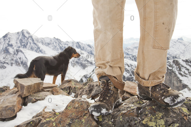 A dog and the legs and boots of hiker on the summit of Frosty Mountain, British Columbia, Canada