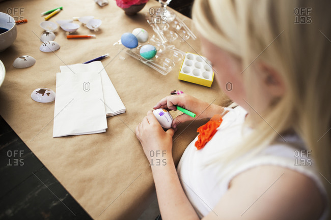 A little girl uses stencils to decorate Easter eggs