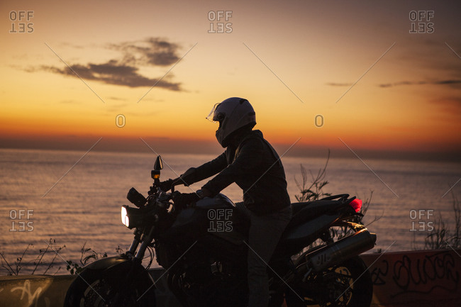 Man on motorcycle by sea