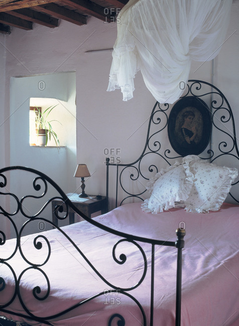 Room with an iron bed and pink blanket
