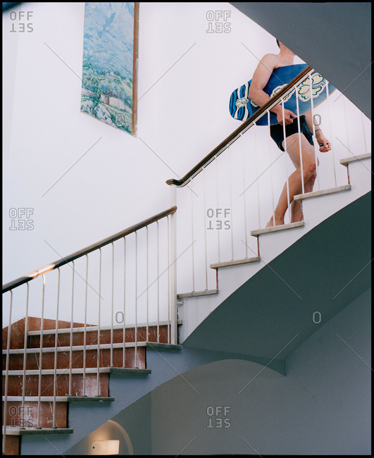 Man walking upstairs carrying a skimboard