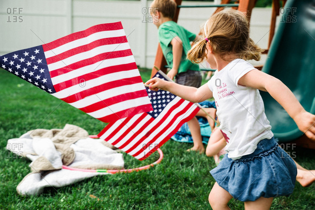 Children running in backyard with American flags