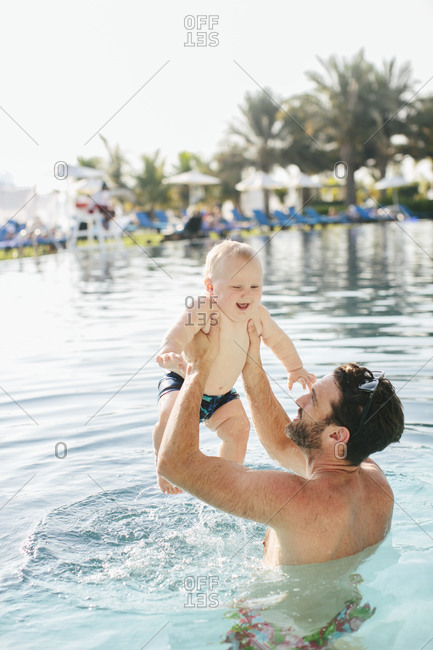 Father lifting baby in swimming-pool