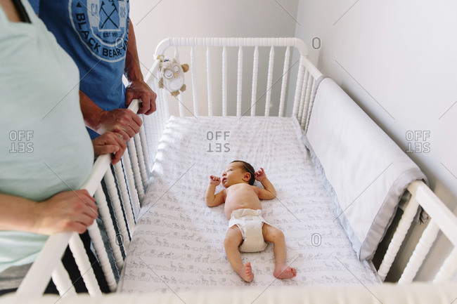 Parents looking down on newborn in crib