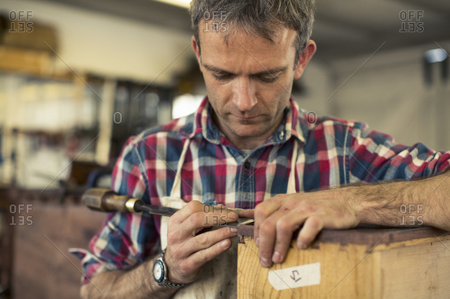 An antique furniture restorer working with chisel