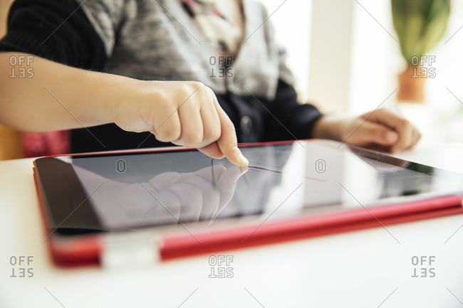 Finger of child drawing letters on digital tablet