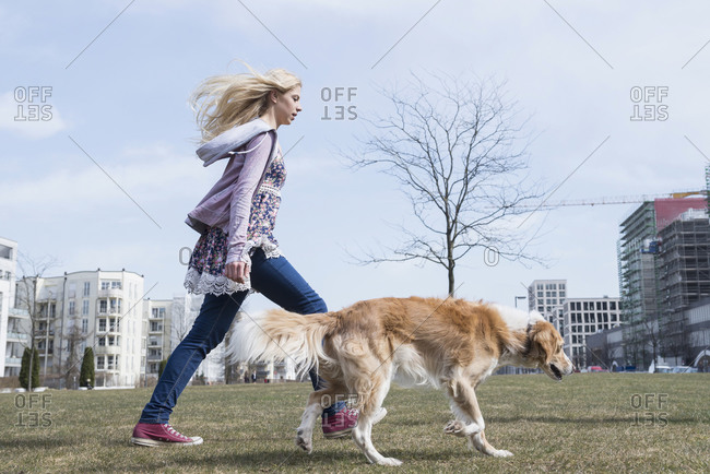 Side profile of teenage girl walking in park with dog