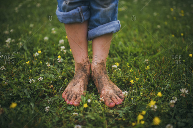 Young girl standing in the grass with dirty feet