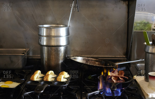 Bacon and eggs cooking on a restaurant stovetop