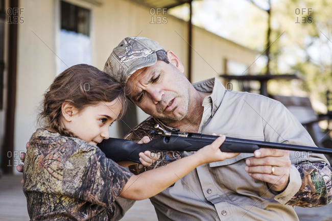 A father shows his daughter how to aim a rifle