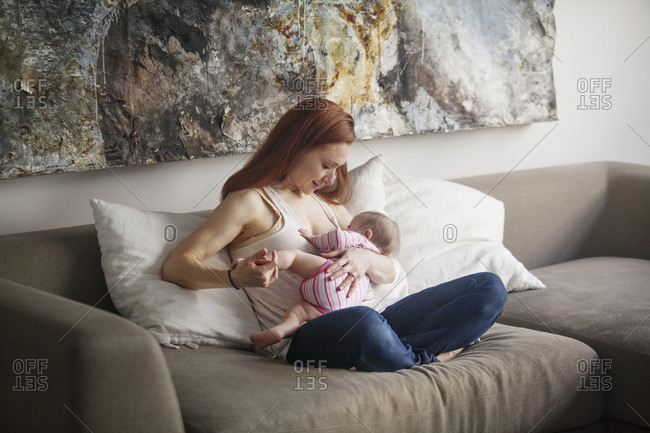 A mother nurses her newborn child in her living room