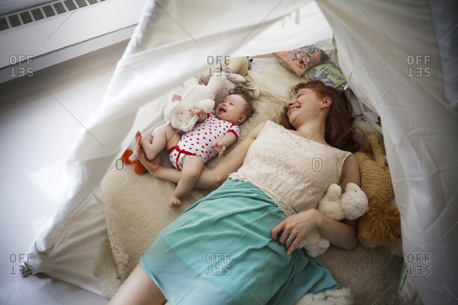 A mother and her baby daughter laugh in an indoor tent