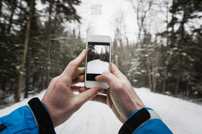 A man takes a picture of a snowy road with his phone