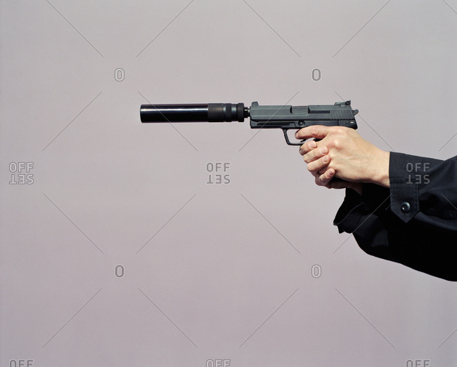 Person\'s hands pointing a handgun with silencer attached