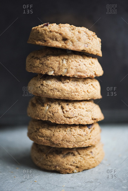 Stack of thick cookies with nuts and chocolate on granite surface