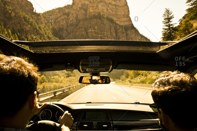 Two friends drive through Glenwood Canyon, Colorado with the sunroof open