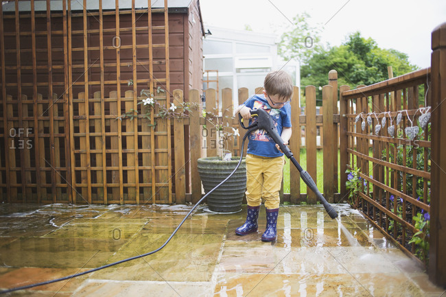 Little boy power washing a patio