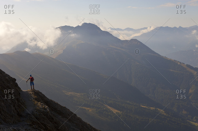 A male hiker enjoys the beautiful view over mountains and valleys, during the Glocknerrunde, a 7 stage trekking from Kaprun to Kals around the Grossglockner, the highest mountain of Austria