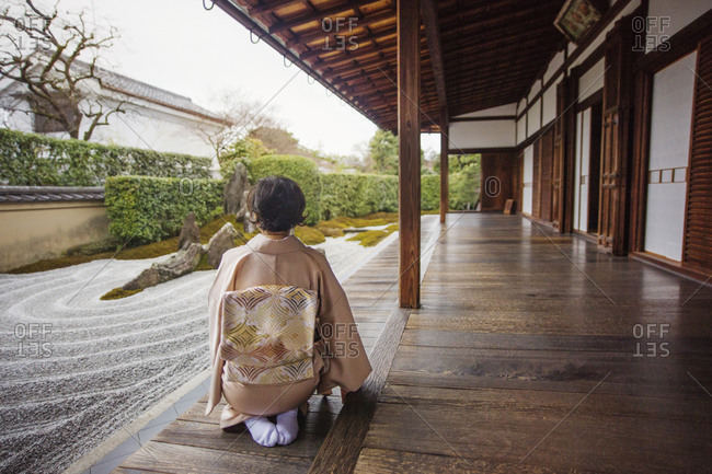 A woman admires a Japanese rock garden from her porch