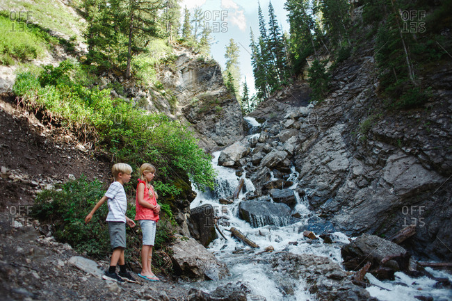 Kids standing by waterfall in mountain woods