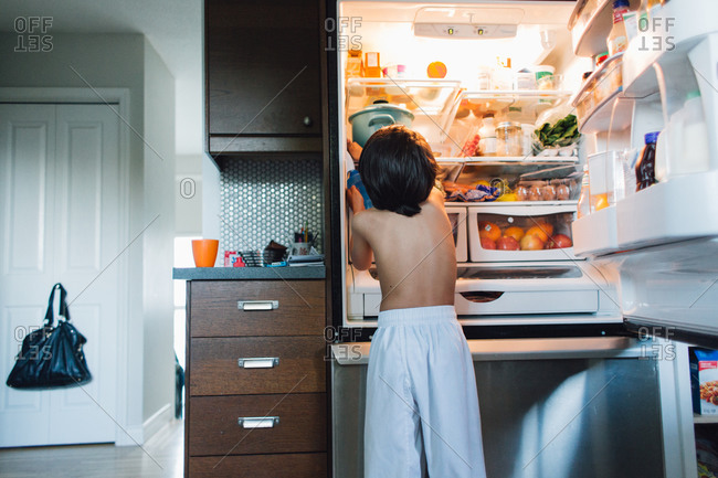 Boy reaching for food in fridge