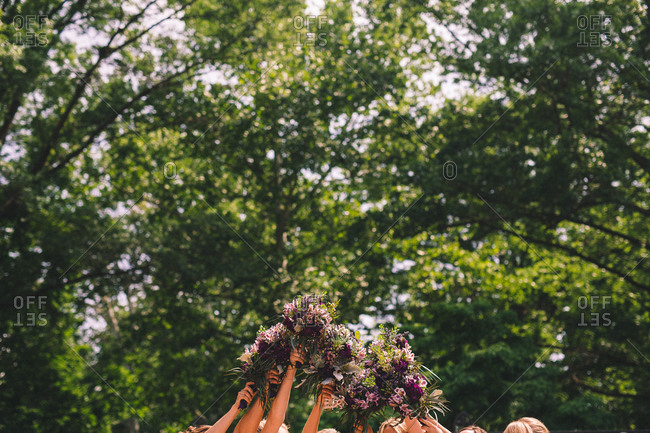 Bridesmaids holding their floral bouquets together up in the air