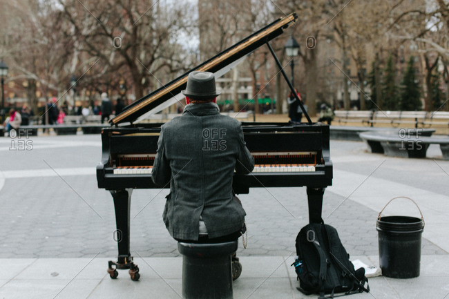 Man playing a piano set up outdoors in a city park