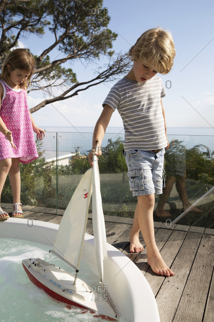 Boy and girl playing with a toy sailboat