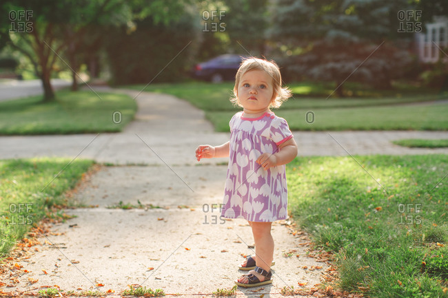 Toddler on suburban sidewalk in summer