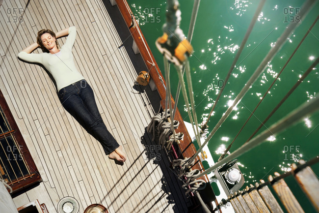 Relaxed mature woman lying on deck of a sailing ship