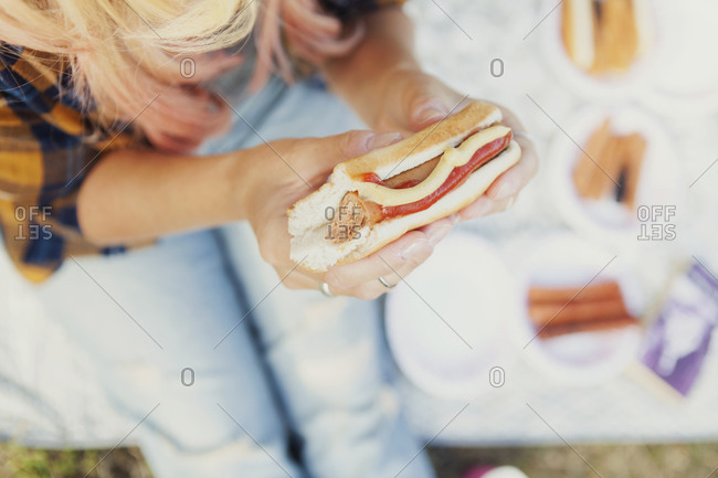 Hot dog with bite missing in woman\'s hands