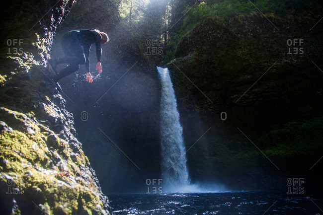 A woman jumps into a swimming hole at Eagle Creek Falls in the Columbia Gorge, Oregon