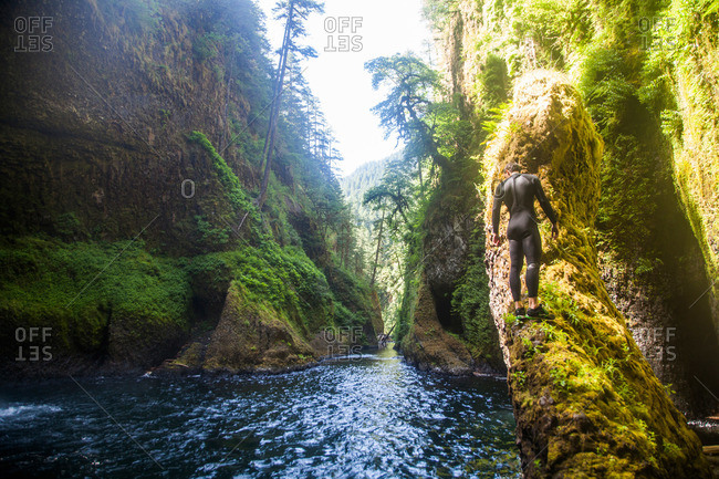 A man walks on the edge of a moss covered rock in Eagle Creek Falls in the Columbia Gorge, Oregon