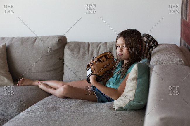 Girl sitting on couch wearing baseball mitt