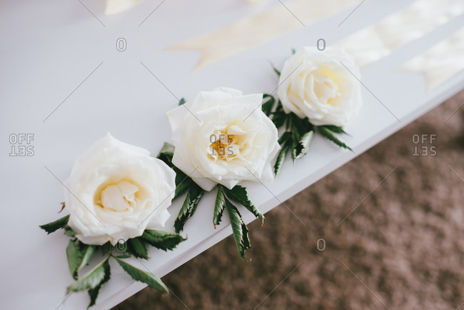 Three white roses on a table at a wedding