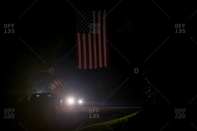 Headlights shine on a Fourth of July flag