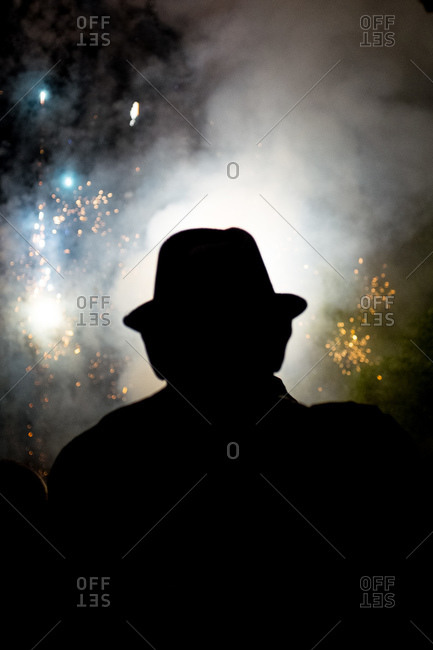 A man in a hat watches Fourth of July fireworks
