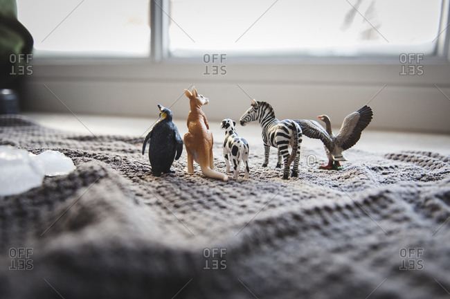 Plastic animal figurines lined up on a blanket