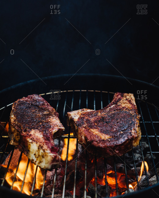 Two thick steaks over a charcoal fire