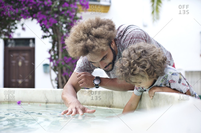 Man plays with son in a fountain