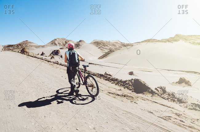 Woman pushing a mountain bike through the Moon Valley, Atacama Desert
