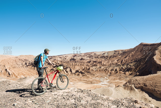 Man holding a mountain bike and looking to the Death Valley in the Atacama Desert