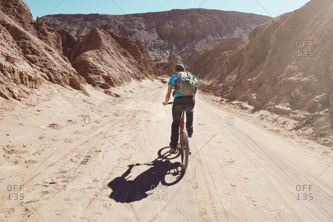 Man riding a mountain bike through the Valle de la Muerte, Atacama Desert