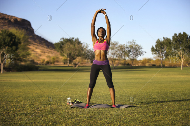 Athletic woman standing on yoga mat stretching